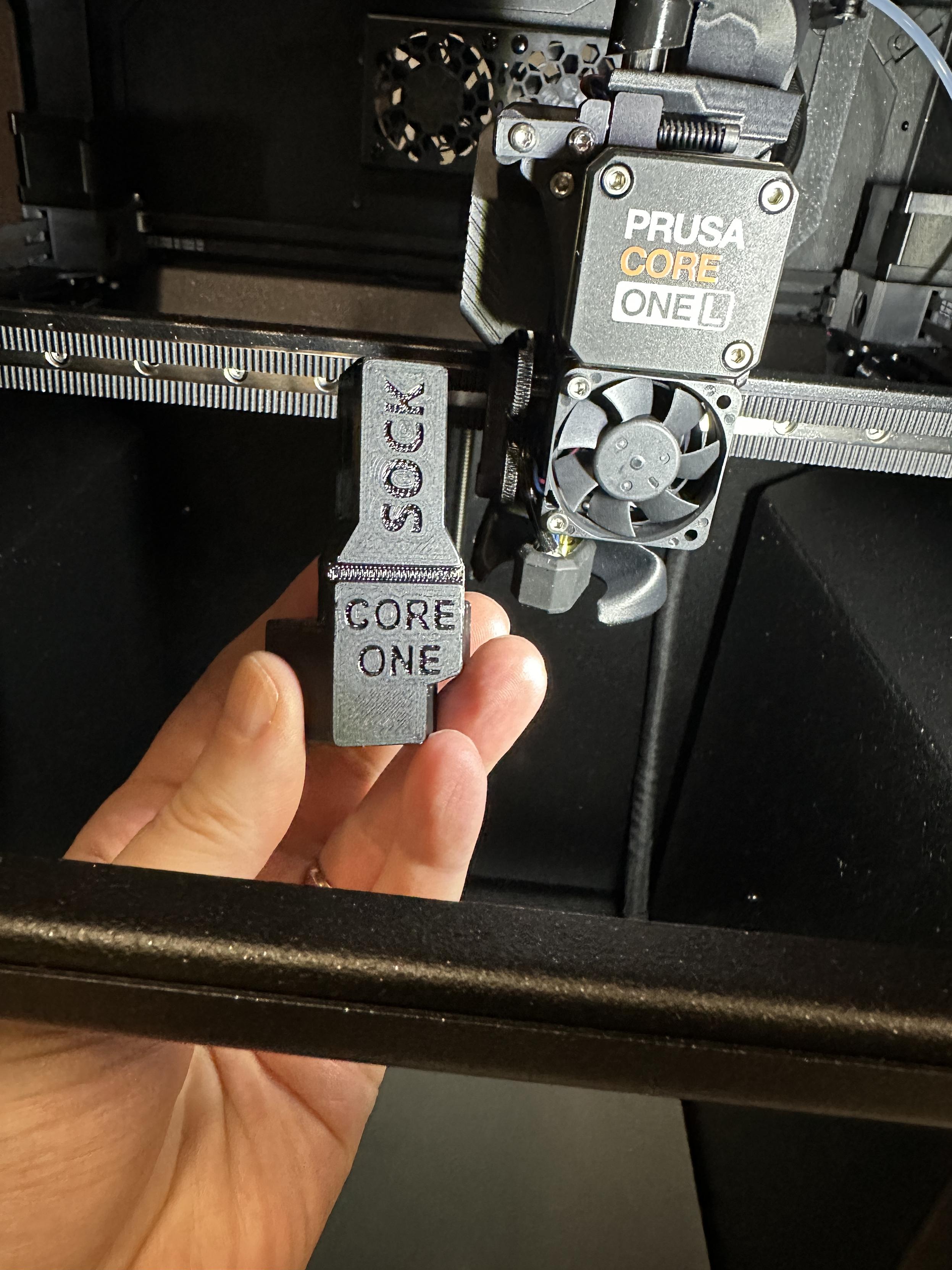 A printable Prusa Core One 3D printer nozzle quick swap tool held in hand